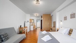 Ein modernes Hotelzimmer mit Bett, Sofa, Schreibtisch und einer Küchenzeile.