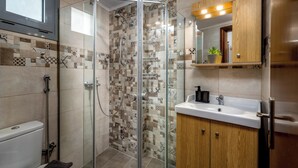 Ein modernes Badezimmer mit einer Duschkabine aus Glas, einem weißen Waschbecken und einem Holzkabinet.