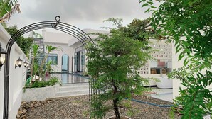 A courtyard with a pool, a pergola, and a small tree. - Tây Homestay 968 (Ninh Thanh)