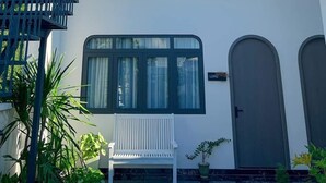 A white building with a staircase, a bench, and a door. - Tây Homestay 968 (Ninh Thanh)