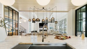 A modern kitchen with a central island, pendant lighting, and a view to the living area. - Personal Sanctuary, comfort and luxury at every turn (Kiawah Island)