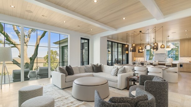 A spacious living area with a large sectional sofa, ottomans, and a dining area with a kitchen in the background. - Personal Sanctuary, comfort and luxury at every turn (Kiawah Island)