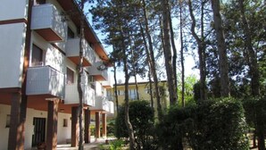 A multi-story building with balconies, surrounded by trees and greenery. - Cozy condo 300mt from the beach (Bibione)