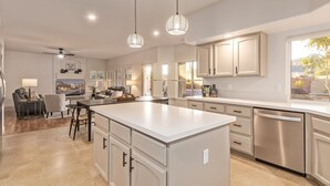 A modern kitchen with a central island, pendant lighting, and a view of the outdoors. - Heated Saltwater Pool • King Beds • Putting Gr •  Mt Views • Game Rm • Sleeps 11 (Phoenix)