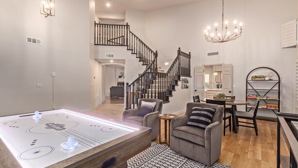 A spacious living room with a wooden floor, a pool table, a grey sofa, and a staircase leading to an upper level. - Heated Saltwater Pool • King Beds • Putting Gr •  Mt Views • Game Rm • Sleeps 11 (Phoenix)