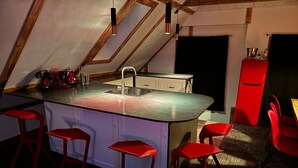 Una cocina moderna con una isla central, taburetes rojos y un refrigerador rojo.