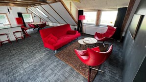 Un interior moderno con un sofá rojo, sillas rojas y una zona de comedor.
