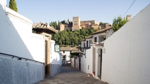 A narrow alleyway with a checkered floor leading to a building with a tiled roof. - Sky is blue Granada with private parking included (Granada)
