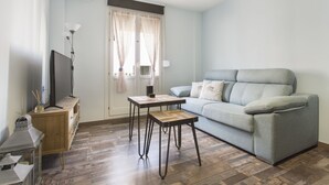 A modern living room with a grey sofa, a small wooden table, and a TV on a wooden cabinet. - Sky is blue Granada with private parking included (Granada)