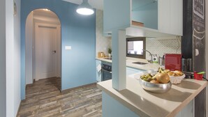 A kitchen with a wooden floor, a sink, a red coffee machine, and a bowl of fruit on the counter. - Sky is blue Granada with private parking included (Granada)
