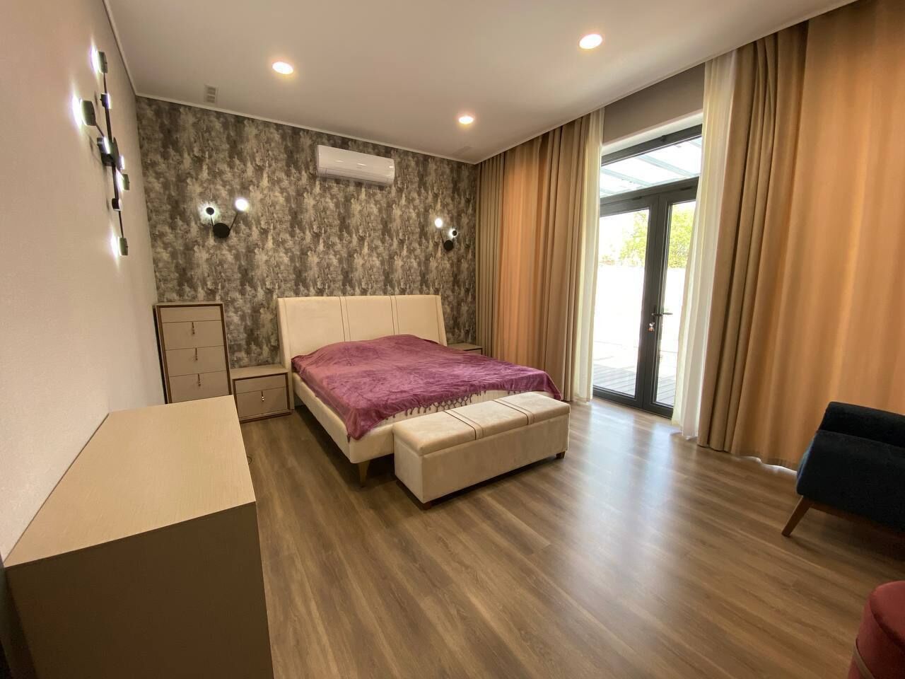 Un dormitorio con cama, banca, armario y escritorio.