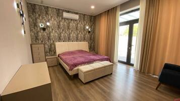 Un dormitorio con cama, banca, armario y escritorio.