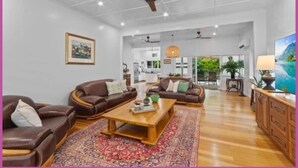 A spacious living room with leather sofas, a wooden coffee table, and a large rug. - The Grand Queenslander On Turner (Pimlico)