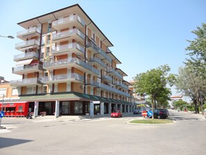 Un hôtel à plusieurs étages, doté de balcons, d’un auvent vert et donnant sur la rue, où l’on peut voir des voitures et un passage piéton.