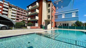 Ett poolområde med en klarblå pool, omgivet av ett staket av metall.