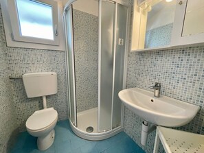 A bathroom with a toilet, a shower enclosure, and a sink.