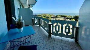 Un balcon avec vue sur la mer, une table et une plante en pot.