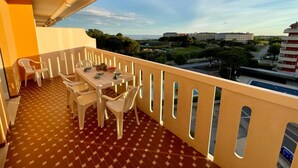 Un balcon avec une table et des chaises, un sol à motifs et une vue sur des immeubles et des arbres.