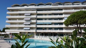 Ett hotell med flera våningar, balkonger, en swimmingpool och en klarblå himmel.