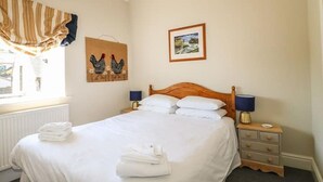 A neatly made bed with white linens, a wooden headboard, and two bedside lamps. - Well Cottage - 2 bedroom (sleeps 4) (Ashbourne)