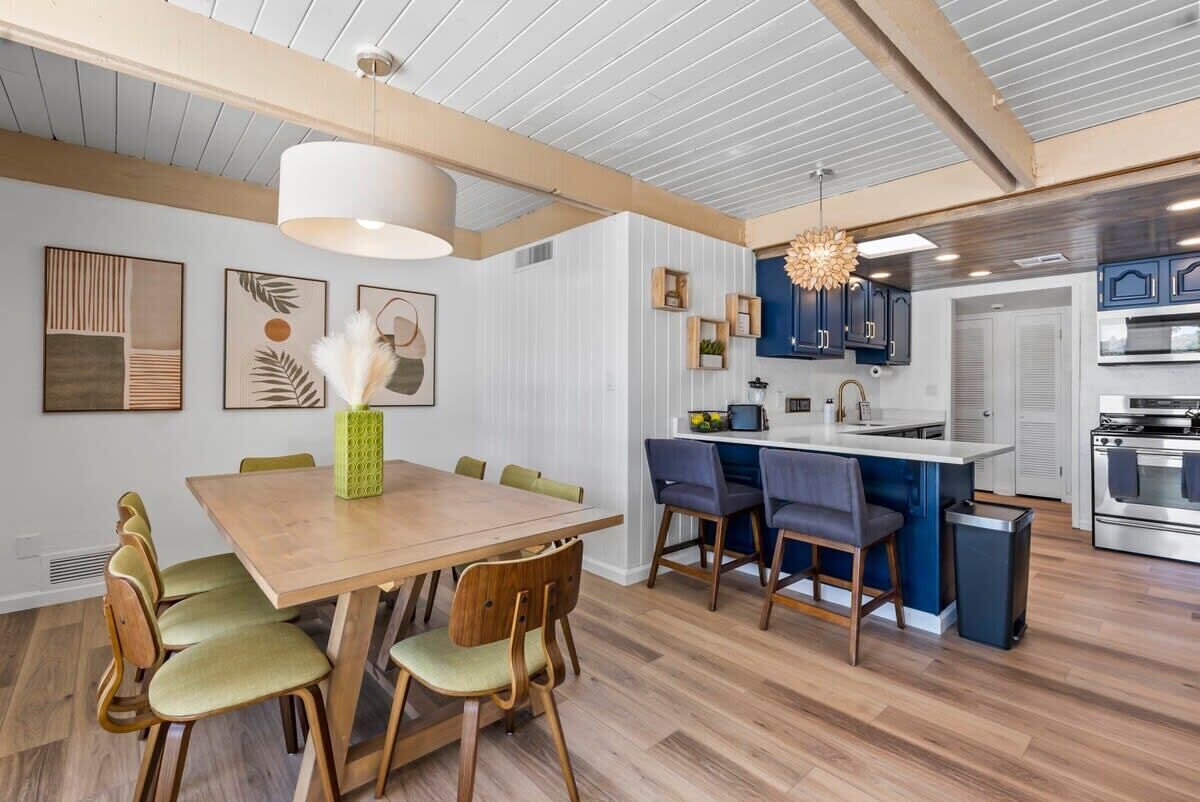 A modern kitchen with a central island, wooden dining table, and chairs.