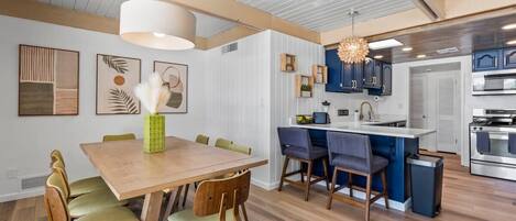 A modern kitchen with a central island, wooden dining table, and chairs.