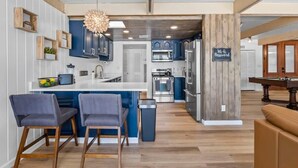 A modern kitchen with blue cabinets, a central island, and a dining area with two chairs. - 6BR Luxury Phoenix Home w Pool, Hot Tub, Games (Phoenix)