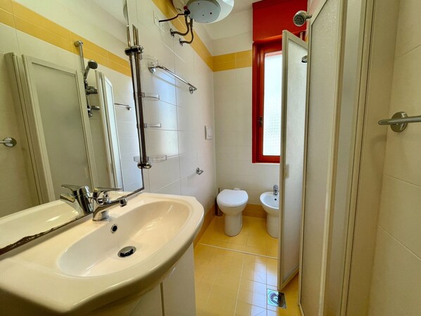 Un baño con lavamanos, espejo, ducha, inodoro y bidé.