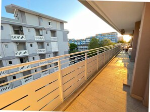A balcony with a railing, a tiled floor, and a view of adjacent buildings.
