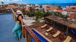 Un complexe hôtelier doté d’une piscine, de chaises longues et offrant une vue sur la plage et l’océan.