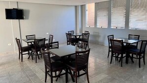 A conference room with multiple tables and chairs, a mounted TV, and large windows with blinds. - Hotel Parati Arapongas (Arapongas)
