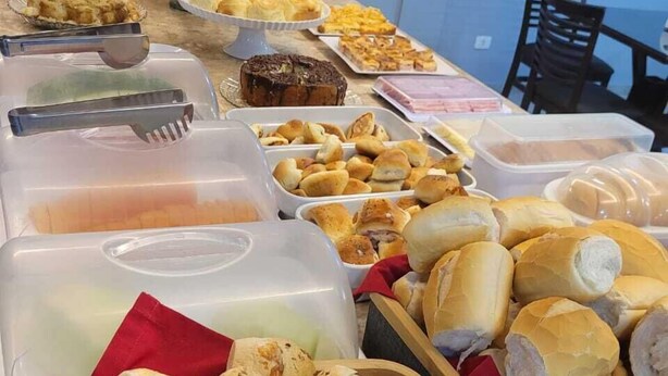 Un tavolo per buffet con diverse pietanze, tra cui panini, pasticcini e dolci.