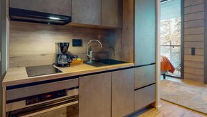 A modern kitchen with built-in appliances, a wooden countertop, and a large window. - Kurula's Resort (Pyhätunturi)
