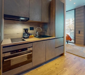Una cocina moderna con electrodomésticos integrados, encimera de madera y un amplio ventanal.