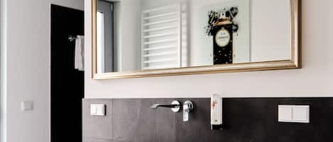 A modern bathroom with a large mirror, a white vessel sink, and a black countertop.