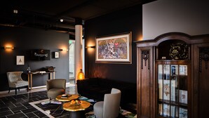 Un hall d’entrée moderne avec un sol carrelé en noir et blanc, un canapé noir, deux fauteuils, une table basse et un meuble avec des portes en verre.