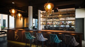 Un espace bar doté d’un comptoir en bois, de tabourets de bar et d’une vitrine en verre remplie de bouteilles.