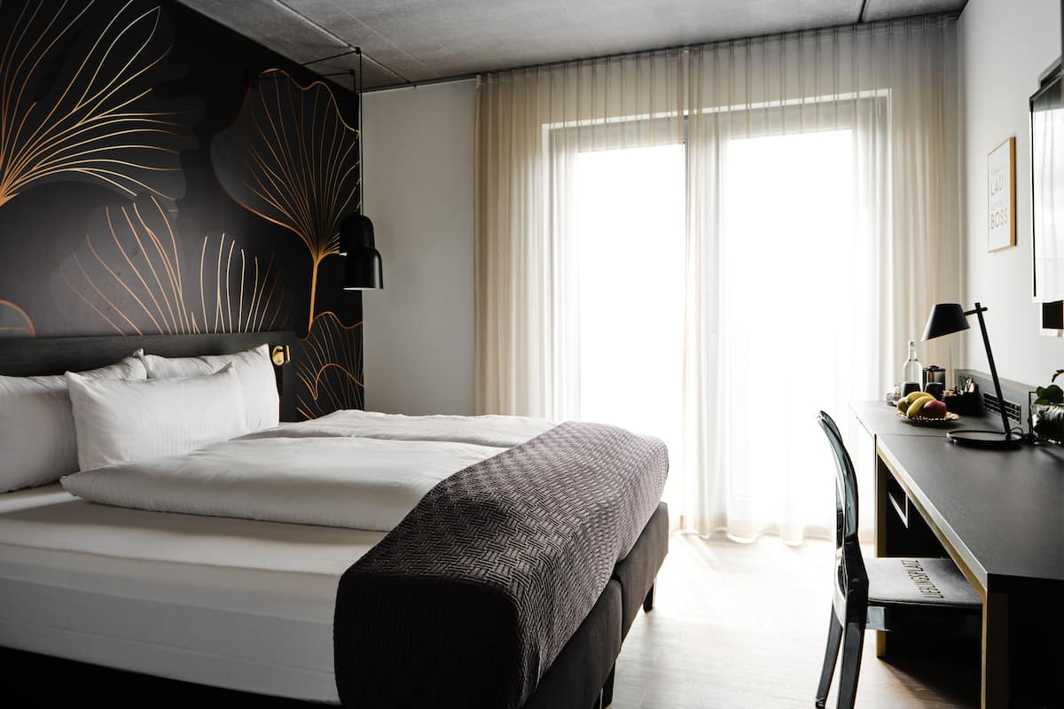 Een moderne hotelkamer met een groot bed, een bureau en een stoel.
