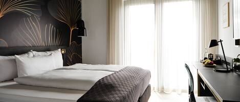Una habitación de hotel moderna con una cama grande, un escritorio y una silla.