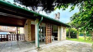 Un patio couvert, avec un bâtiment en briques, une clôture en bois et une voiture garée à l’extérieur.