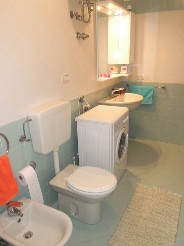 A bathroom with a toilet, sink, and washing machine.