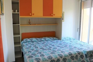Una habitación con una cama, un armario y un estante con un objeto decorativo.