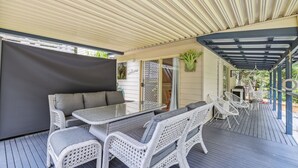 An outdoor patio with a covered seating area, a table, and chairs. - Safety Beach Cottage (Safety Beach)