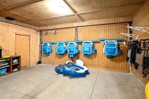 A garage with wooden walls, a concrete floor, and various blue kayaks and a white canoe. - 6 Bedroom | 7 King Beds | Elevator | Beachfront (Navarre)