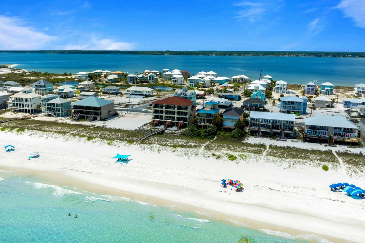 A coastal resort with beachfront villas, a sandy beach, and clear blue waters.