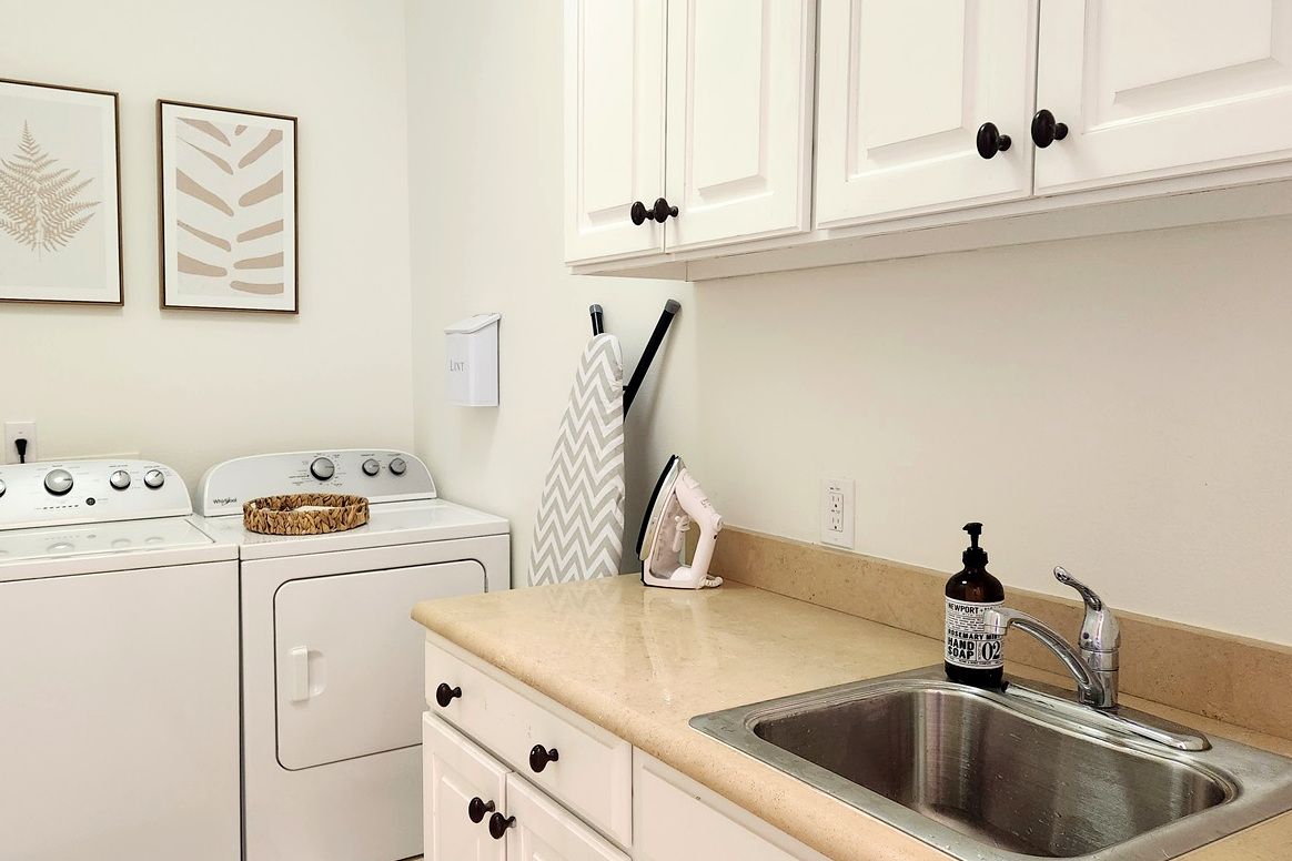 A kitchen with a stainless steel sink, a washing machine, and a stove.