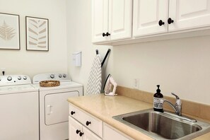 A kitchen with a stainless steel sink, a washing machine, and a stove. - 6 Bedroom | 7 King Beds | Elevator | Beachfront (Navarre)