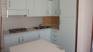 A compact kitchen with light blue cabinets, a gas stove, and a sink.