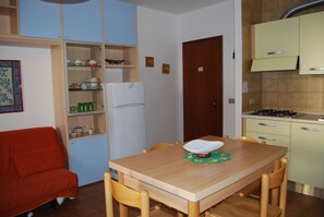 Una cocina compacta con mesa, sillas, refrigerador y estufa.