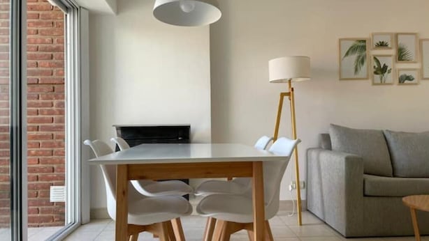 A modern dining area with a white table and chairs, a floor lamp, and a grey sofa.